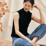 Woman sitting on bench in black sleeveless velvet mandarin collar qipao style blouse, casual elegant look