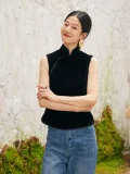 Model with crossed arms in black sleeveless velvet mandarin collar qipao style blouse, elegant and modern