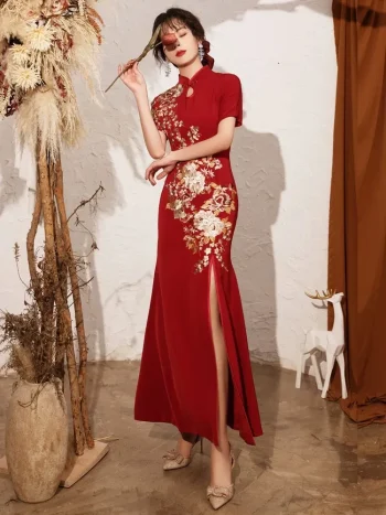 Chinese qipao wedding dress in a styled pose with a rose, showcasing premium floral embroidery and a sleek high-slit design for bridal photoshoots and receptions.