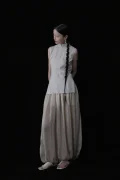 Full body side view of a cheongsam style top with a traditional cheongsam collar, sleeveless pinstripe design, and tailored fit, styled with flowy wide leg pants for a timeless look.