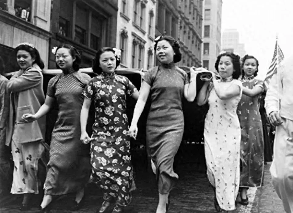 Black and white historical photo of women in 1930s traditional qipao cheongsam dresses parading in New York, showcasing the early style of Chinese qipao dress and the global spread of cheongsam culture.