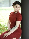 Side view of woman in plus size red long cheongsam, showing flattering silhouette while sitting outdoors