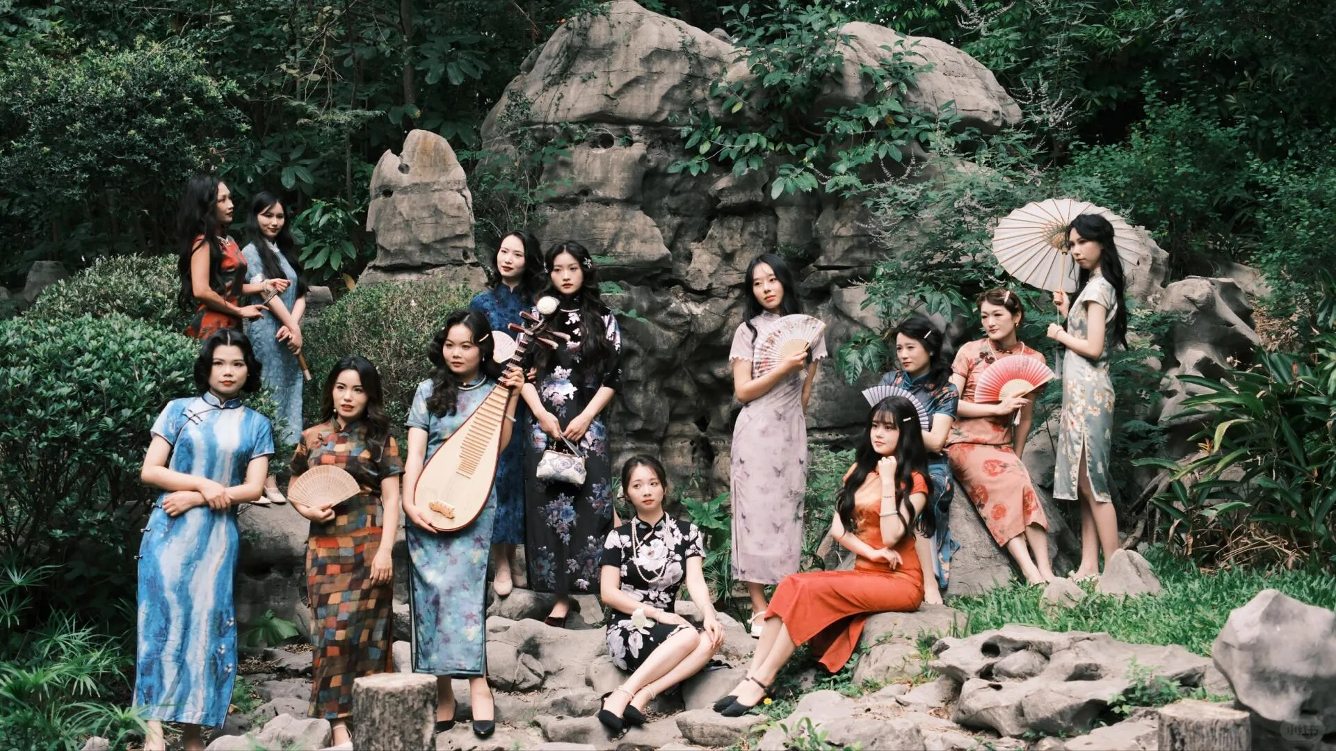 Group of women in various traditional and modern qipao cheongsam dresses posing in a Chinese garden, featuring styles from floral prints to solid colors with props like pipa and fans, ideal for understanding the versatility of cheongsam dresses.