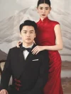 Romantic intimate couple wedding photo, bride in red long wedding cheongsam standing behind groom in black tuxedo, classic chinese bridal qipao for prewedding shoot