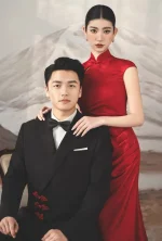 Romantic intimate couple wedding photo, bride in red long wedding cheongsam standing behind groom in black tuxedo, classic chinese bridal qipao for prewedding shoot