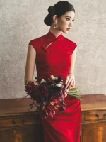 Profile view bridal solo portrait, woman in red long wedding cheongsam holding bridal bouquet, classic chinese bridal qipao with vintage textured wall background