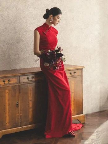 Side view bridal solo portrait, woman in red long train wedding cheongsam holding dark red bridal bouquet, leaning on vintage wooden cabinet, traditional chinese wedding qipao