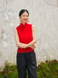 Front view of woman in red sleeveless chinese cheongsam blouse, modern cheongsam style velvet top with crossed arms