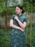 Side view of plus size modern cheongsam in green fabric, flattering fit for curvy women in bamboo garden