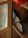 Black Margarita 1920s vintage schoolgirl leather Qipao Mary Jane shoes with delicate brogue stitching, displayed by a wooden window for warm retro ambiance.