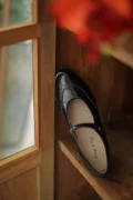 Black Margarita 1920s vintage schoolgirl leather Qipao Mary Jane shoes with delicate brogue stitching, displayed by a wooden window for warm retro ambiance.