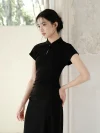Close up side view of a woman in a black qipao dress. The women qipao features a fitted silhouette, cap sleeves, and a subtle keyhole detail at the stand collar, highlighting its modern elegant design.