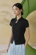 Model wearing a black qipao inspired top, a tailored black chinese mandarin collar qipao top, showing the slimming silhouette and clean lines in a soft studio setting.