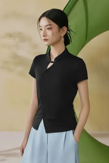 Model wearing a black qipao inspired top, a tailored black chinese mandarin collar qipao top, showing the slimming silhouette and clean lines in a soft studio setting.