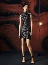 Model posing in a sleek black silk mini cheongsam dress with all-over koi fish brocade, showcasing the modern take on traditional Chinese fashion in a warm-toned studio environment.