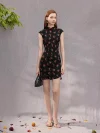 Woman in a black sleeveless short qipao dress with rose print, holding a handbag while standing in a studio, showcasing the dress's modern and elegant summer style.