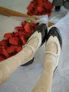 Two-tone black and white Margarita 1920s vintage schoolgirl leather Qipao Mary Jane shoes worn with lace-patterned white socks, styled with red rose petals for old Shanghai aesthetic.