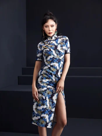 Full front view of a woman wearing a blue crane print slim-fit midi cheongsam dress, highlighting the intricate crane and floral print, short sleeves with black trim, and tailored fit of this elegant midi cheongsam.