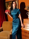 Model in a luxurious blue silk jacquard long chinese qipao dress with high side slit, short sleeves and traditional frog buttons, styled in a vintage home setting with classic furniture and warm lighting.