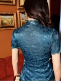 Back view of a blue silk jacquard qipao dress, showing the hidden back zipper, high mandarin collar, and intricate floral pattern on the smooth, lustrous fabric.