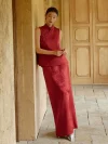 Two-piece Burgundy Modified Qipao With Pants (or Matching Skirt) - Woman in elegant burgundy qipao set with sleeveless mandarin collar brocade top and coordinating maxi skirt, leaning against a stone wall in a sunlit classic corridor, modern chinese dress qipao for formal events and weddings