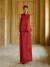 Two-piece Burgundy Qipao With Pants Set - Full body shot of woman in burgundy modified qipao set, featuring a sleeveless mandarin collar brocade top and coordinating maxi skirt, standing centered in a classic sunlit corridor