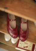 Top-down view of Burgundy Red Margarita 1920s Vintage Schoolgirl Style Leather Qipao Mary Jane Shoes, showcasing the elegant brogue design on a wooden shelf.