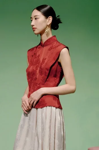 Side profile shot of a model wearing a cheongsam top modern style, a women's red chinese slim fit jacquard cheongsam top, highlighting the clean lines and structured fit.