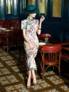 Woman seated in a vintage restaurant, wearing a Chinese silk white floral qipao dress, holding a pearl clutch and showcasing the delicate floral print and tailored fit.