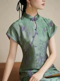 Close-up of women's green modified qipao dress, focusing on the traditional purple frog buttons, mandarin collar, and textured floral 3D cut flower craft on the short sleeve cheongsam