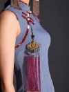 Close-up view of the decorative pink tassel and red frog buttons on a misty blue short cheongsam dress, showcasing the intricate details of this women's cheongsams qipao.