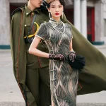 Elegant woman in a dark green brown tone 1930s long mulberry silk qipao, posing with a man in vintage military uniform, showcasing the dress's high collar, frog buttons, and classic 1930s silhouette in a retro Shanghai street setting.