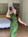 ortrait of a plus size woman in dark green print qipao dress, classic chinese cheongsam with short sleeves and subtle floral print, posing playfully with a folding fan in a bright bedroom setting.