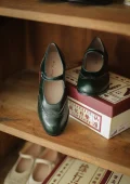 Rich emerald green Margarita 1920s vintage schoolgirl leather Qipao Mary Jane shoes with intricate brogue detailing, displayed on a vintage wooden shelf for nostalgic retro look.