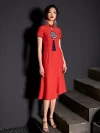 Front view of a woman model wearing a red vintage modified cheongsam dress with intricate embroidery and tassel detail, classic yet modern style.