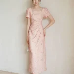 Full-body view of women's summer modified cheongsam, new Chinese style long dress with square neck puff sleeve, waist cinched pleated design in soft pink textured fabric for weddings & summer parties