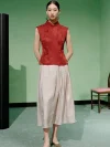 Full-body view of a model wearing a women's red chinese slim fit jacquard cheongsam top, a red modern mandarin collar cheongsam top, styled with a light jacquard midi skirt and gold shoes.