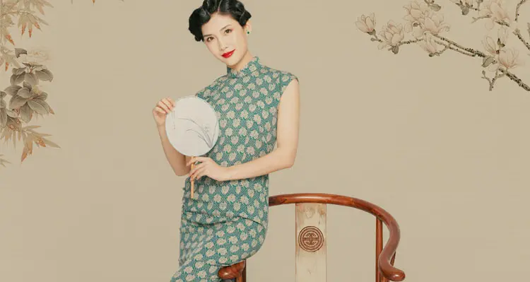Woman wearing green floral sleeveless chinese cheongsam blouse, vintage qipao style top with a round hand fan in traditional chinese painting background