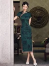 Front view of a woman in dark green vintage floral qipao standing by a stone pillar, displaying traditional frog buttons and full-length design.