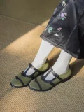 Green Lolita vintage Mary Jane T-strap flat shoes worn with an embroidered black cheongsam skirt and white socks, showcasing retro elegance under natural light