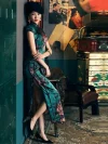 Woman leaning against a wall, wearing a 19 Mome mulberry silk Old Shanghai peony cheongsam with high slit, holding a clutch, in a moody retro interior setting.