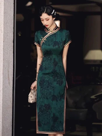 Full-length view of a woman in dark green vintage floral qipao, holding a delicate handbag to highlight the form-fitting cut and high collar.