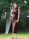 Full body view of women's long vintage floral high cut sleeveless qipao (cheongsam) with red dragon print on black fabric, model standing outdoors with one hand on hip, wearing black Mary Jane shoes.