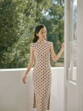 Full-body shot of a woman in a Hong Kong style cotton qipao dress by the window, featuring cap sleeves and a fitted silhouette for modern everyday wear.