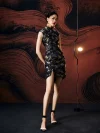 Model in ink black silk mini cheongsam dress with hands behind back, highlighting the high front slit, luxurious satin sheen, and vibrant koi fish pattern in a modern studio setting.