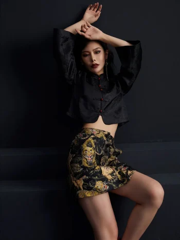 Full-body fashion shot of the ink black tiger jacquard high waist A-line short skirt, paired with a traditional Chinese cropped jacket, showcasing the bold tiger pattern and structured A-line silhouette; stylish black short skirt for modern outfits
