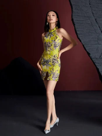Front view of a woman wearing the modernized lemon yellow short qipao dress with grey floral jacquard pattern, featuring halter neck, keyhole detail, and side slit; form-fitting women's qipao dress for contemporary fashion