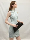 Elegant model holding a black clutch, wearing a light blue modern Chinese sleeveless short cheongsam dress, showcasing the delicate floral jacquard fabric and tailored silhouette.
