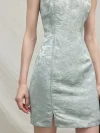 Detailed view of the floral jacquard fabric and front slit of a light blue modern Chinese sleeveless short cheongsam dress, emphasizing the tailored fit.