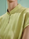 Woman wearing a light green modern cheongsam shirt crafted from mulberry silk, highlighting the delicate stand collar and water drop cutout design at the neckline of this elegant short sleeve qipao top.